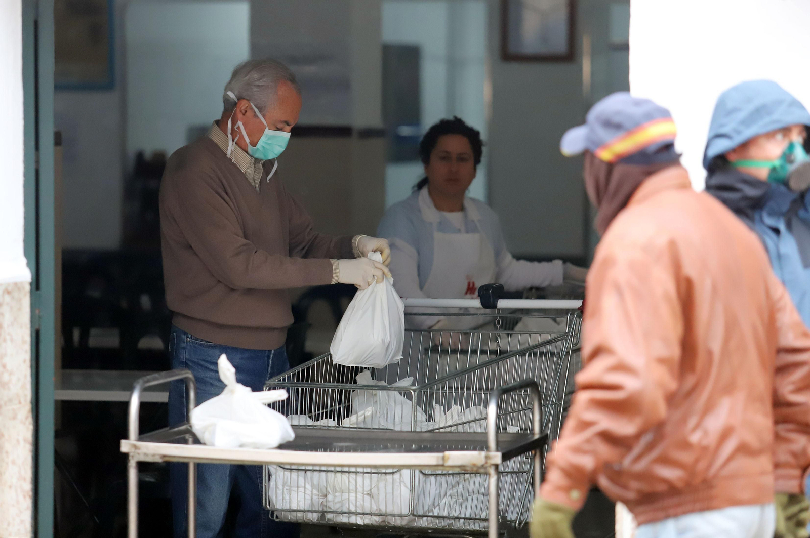 Varias personas reciben alimentos en un comedor social onubense durante la pandemia.