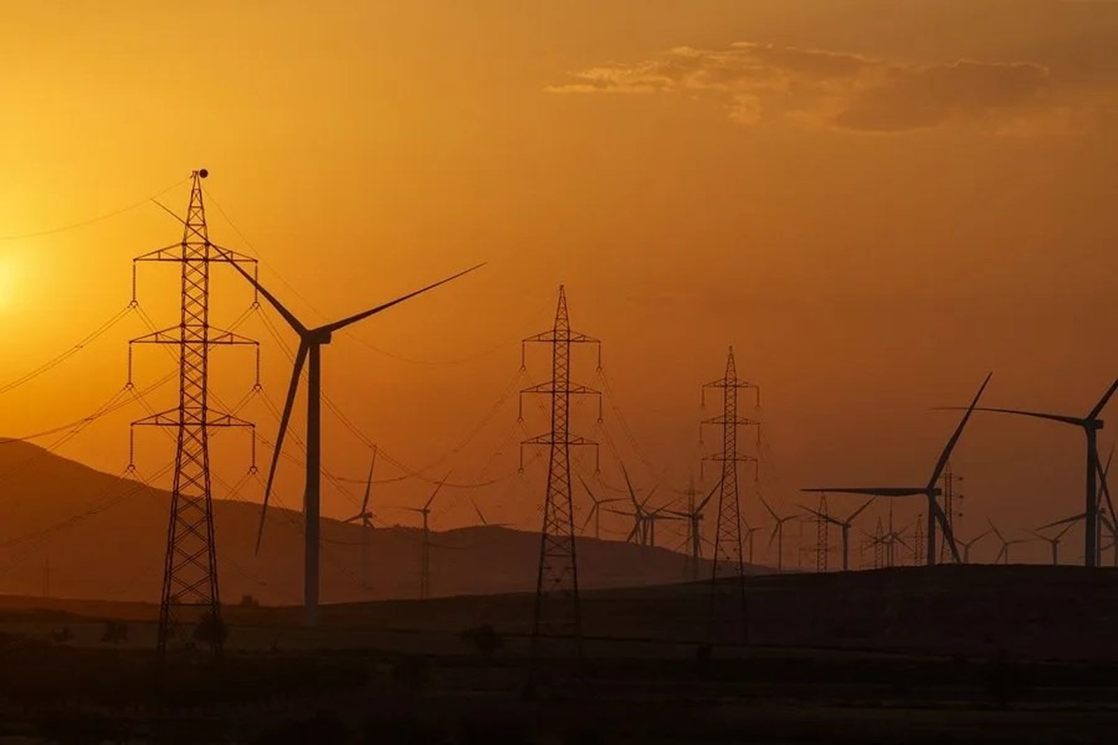 Torres eléctricas junto a un parque eólico.