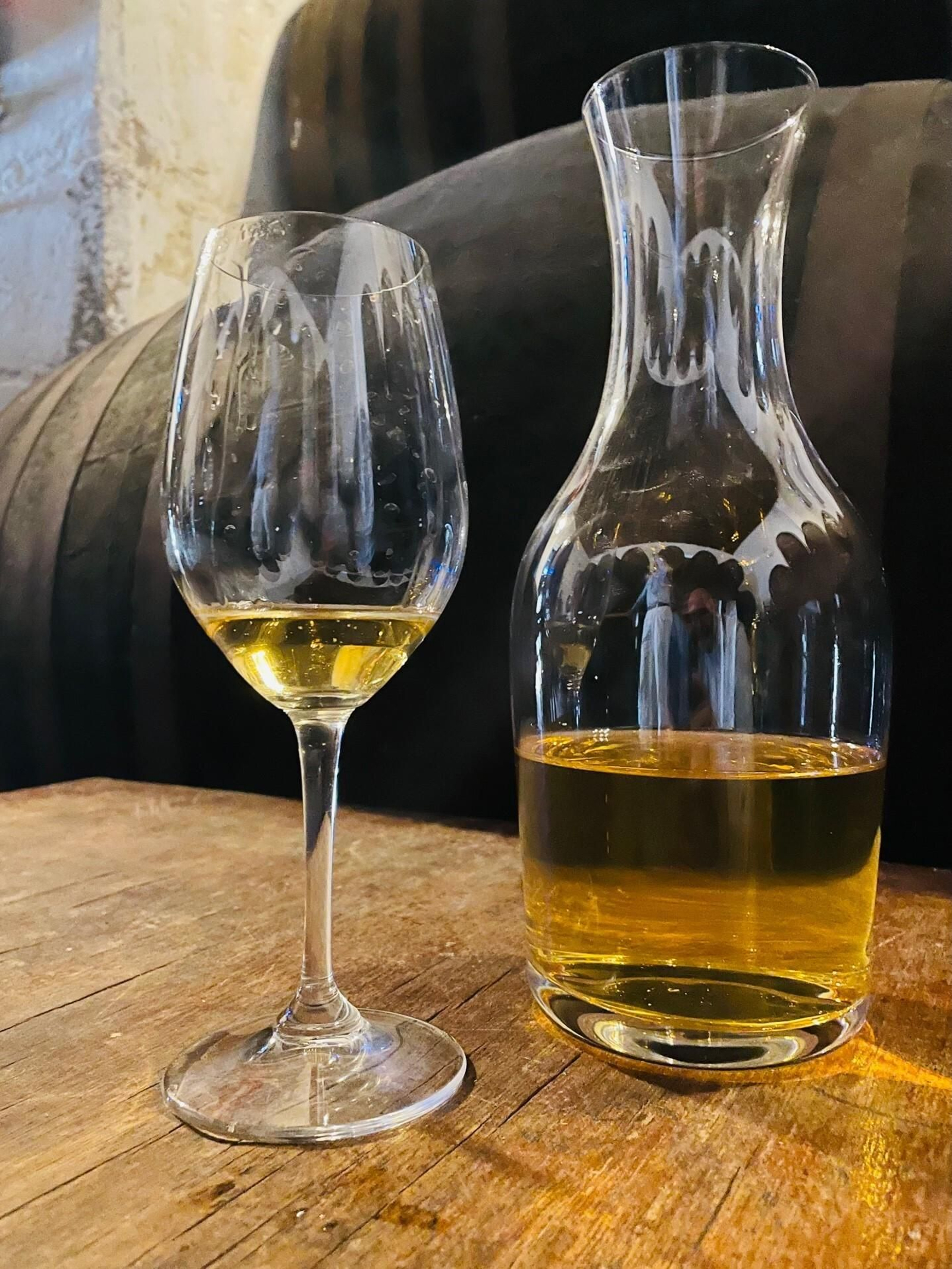 Decantador y copa de vino junto a una andana de botas.