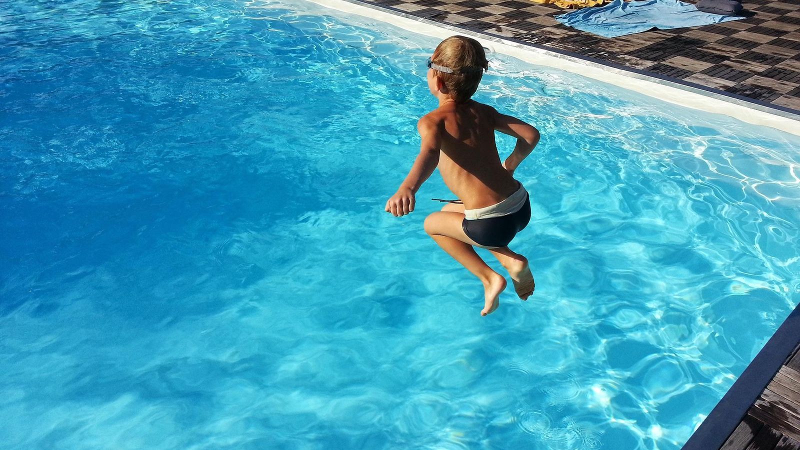 Un niño se lanza de pie a la piscina