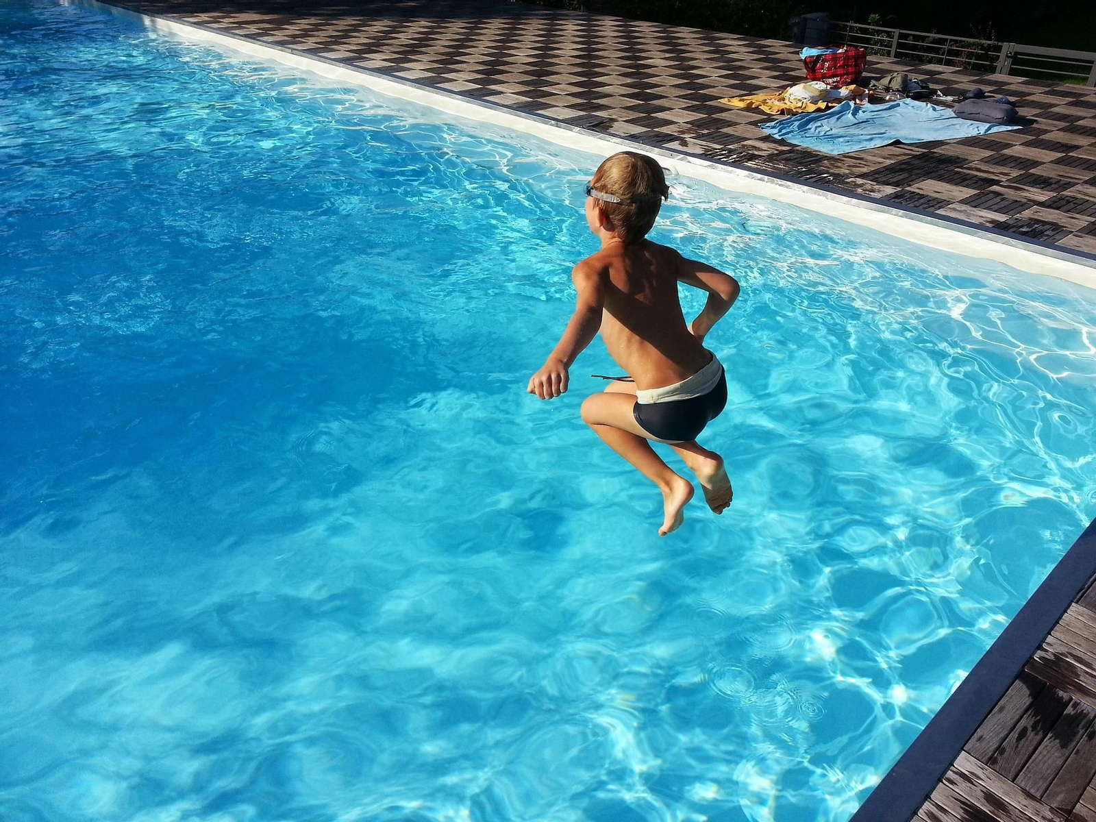 Un niño se lanza de pie a la piscina