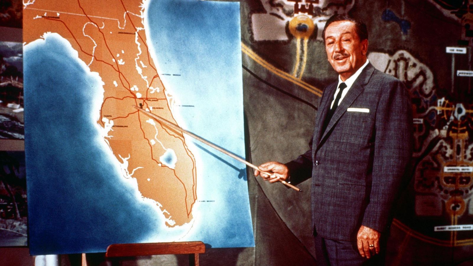 Walt Disney señala su parque de atracciones en un mapa.