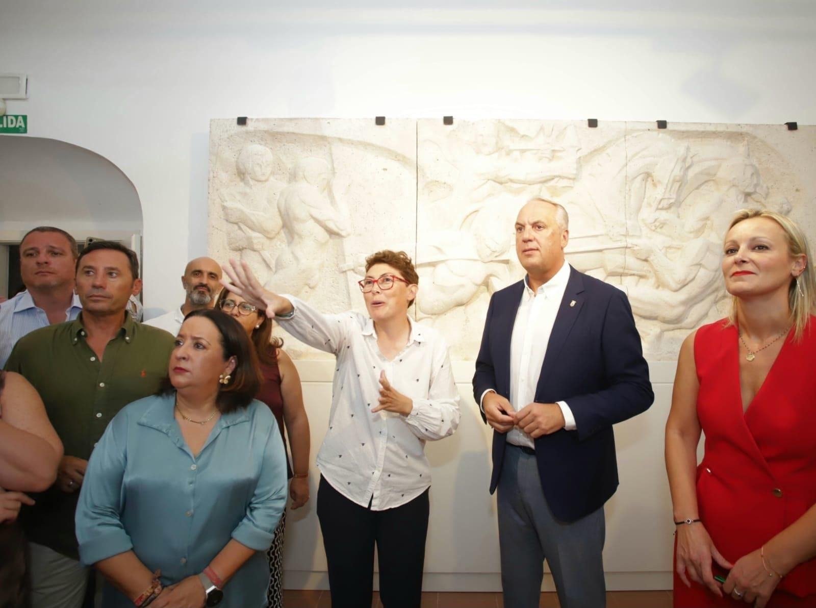 Juan Carlos Ruiz Boix, Ana Ruiz y otras autoridades escuchan explicaciones sobre la muestra junto al relieve que el artista talló para la capilla de San Felipe Neri