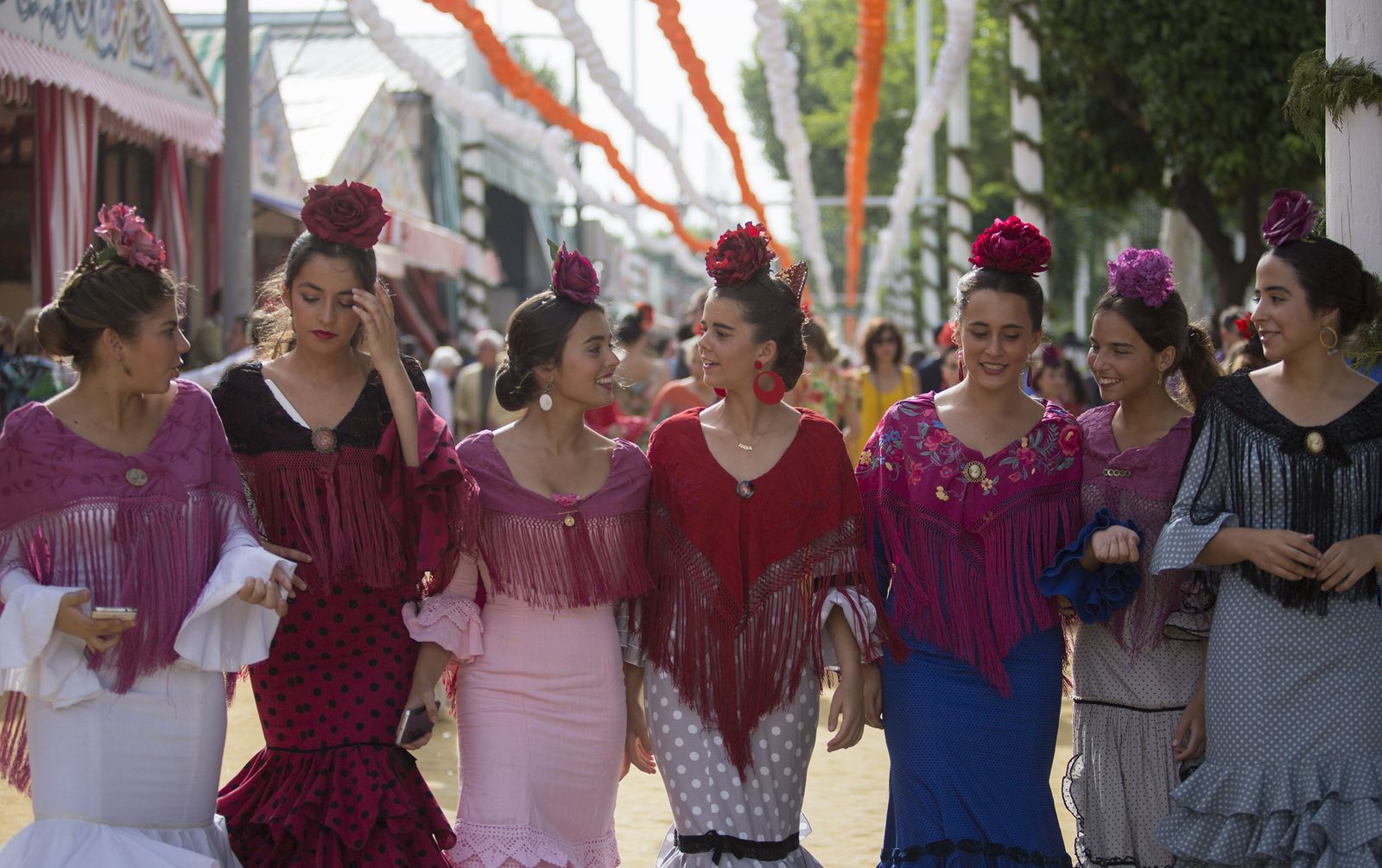 Paseo de mujeres con el real. Todas con el mantón y el clavel en la cabeza. Un cartel vivo de fiestas primaverales.