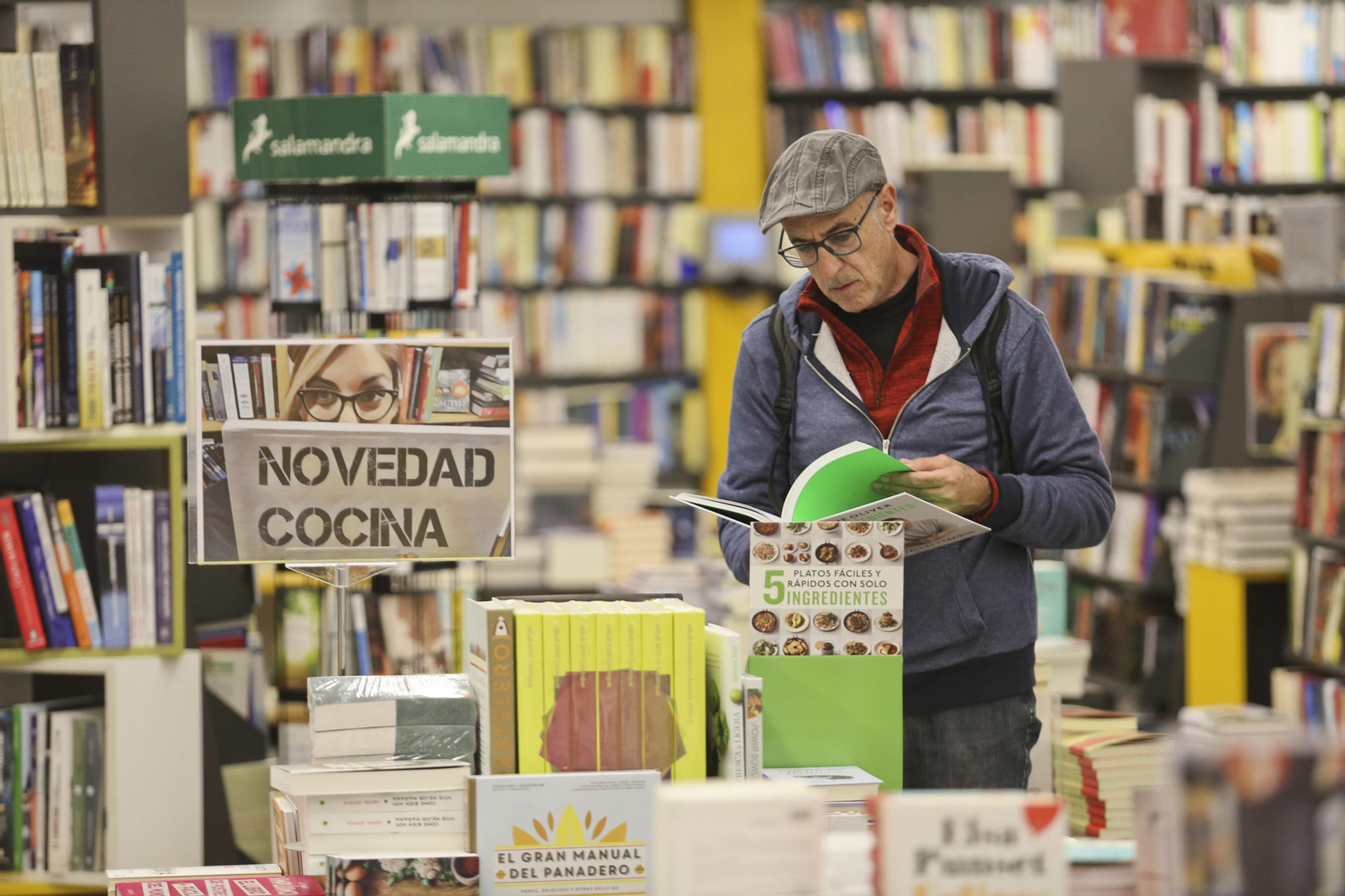 Un hombre hojea un libro en una librería.