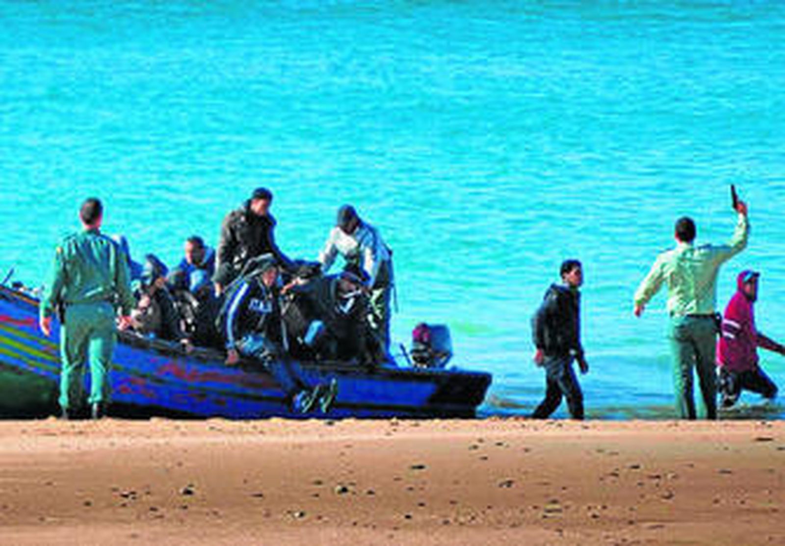 El agente, pistola en mano, en la playa de Los Castillejos, el viernes.