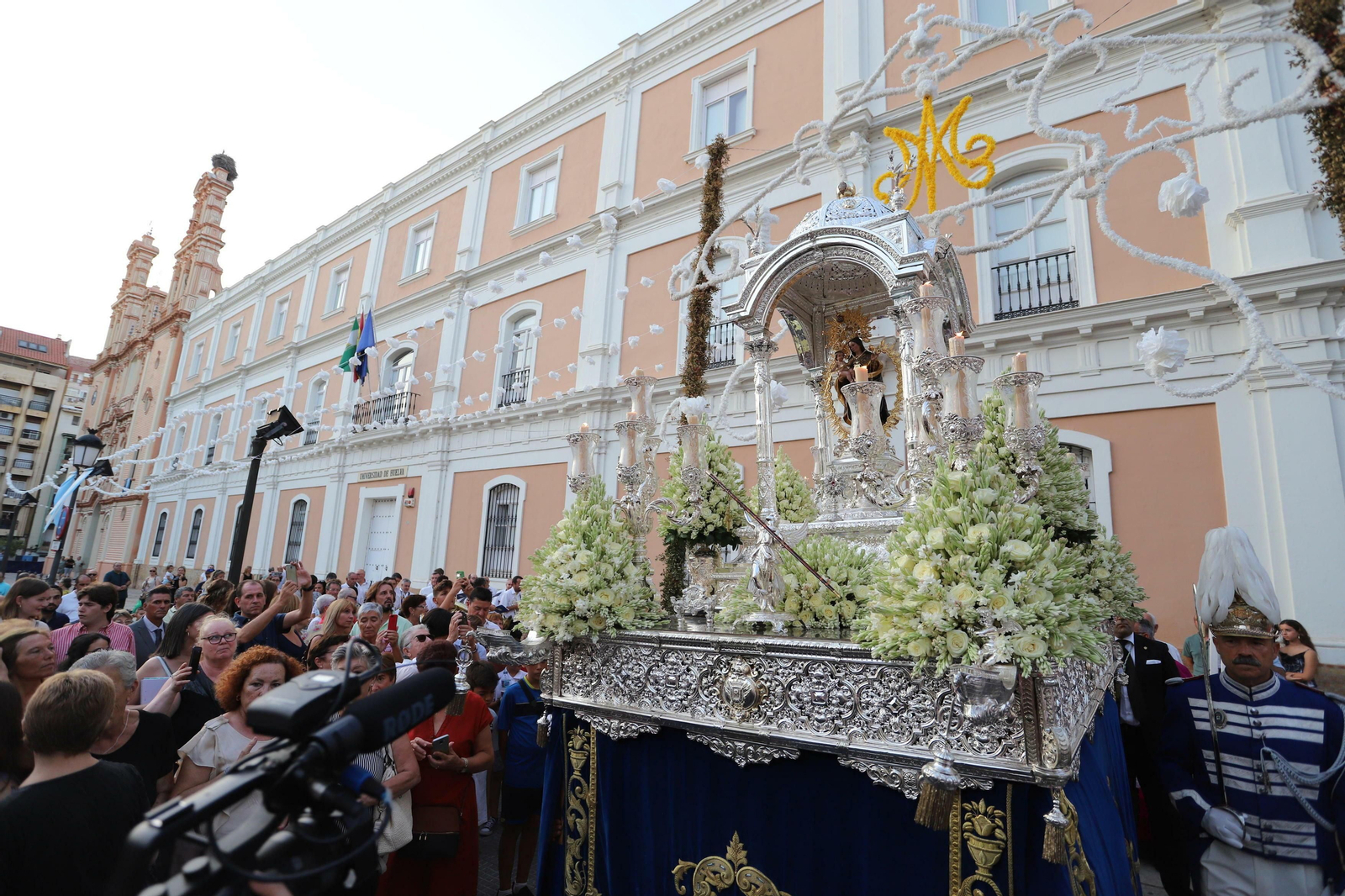 La Virgen de la Cinta cruza el arco de flores de papel instalado en su honor al final del porche de La Merced.