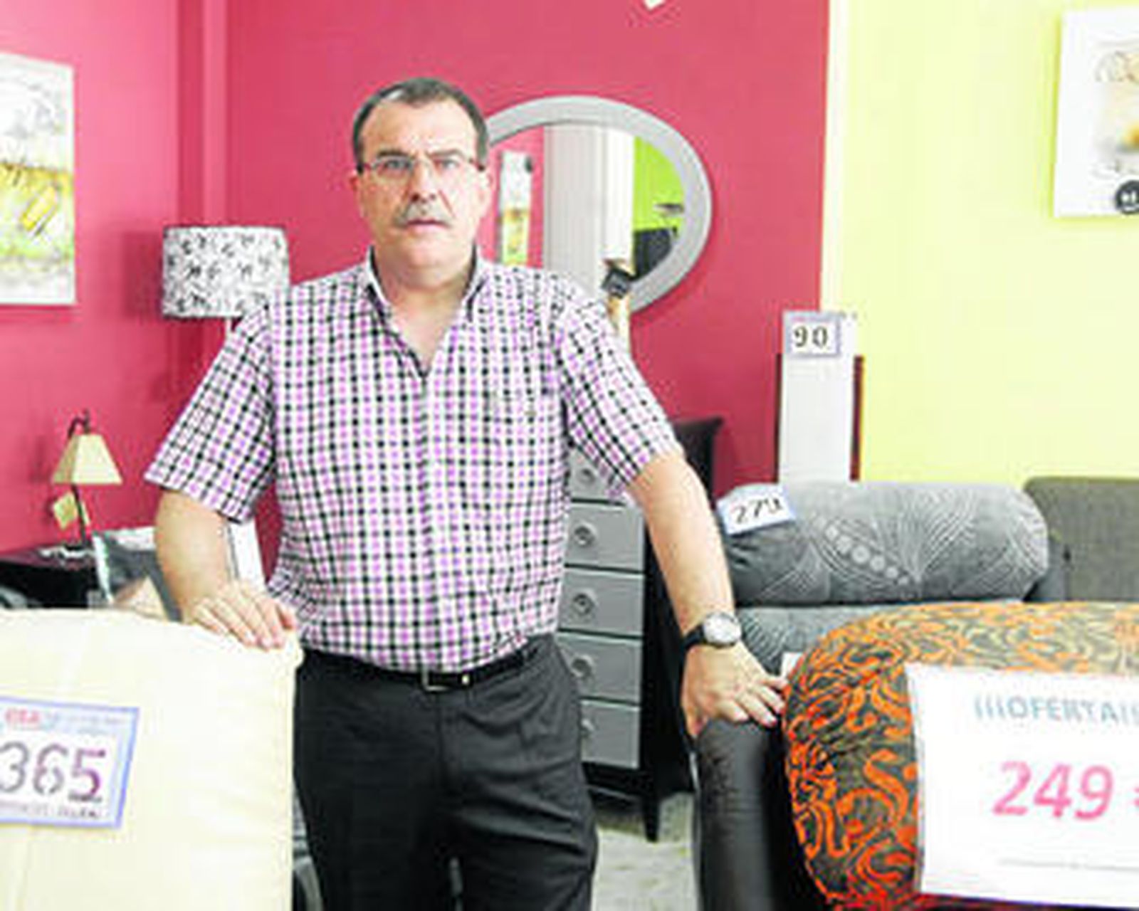 Luis junto a dos sofás de su negocio, Muebles La Constancia, en Maracena.