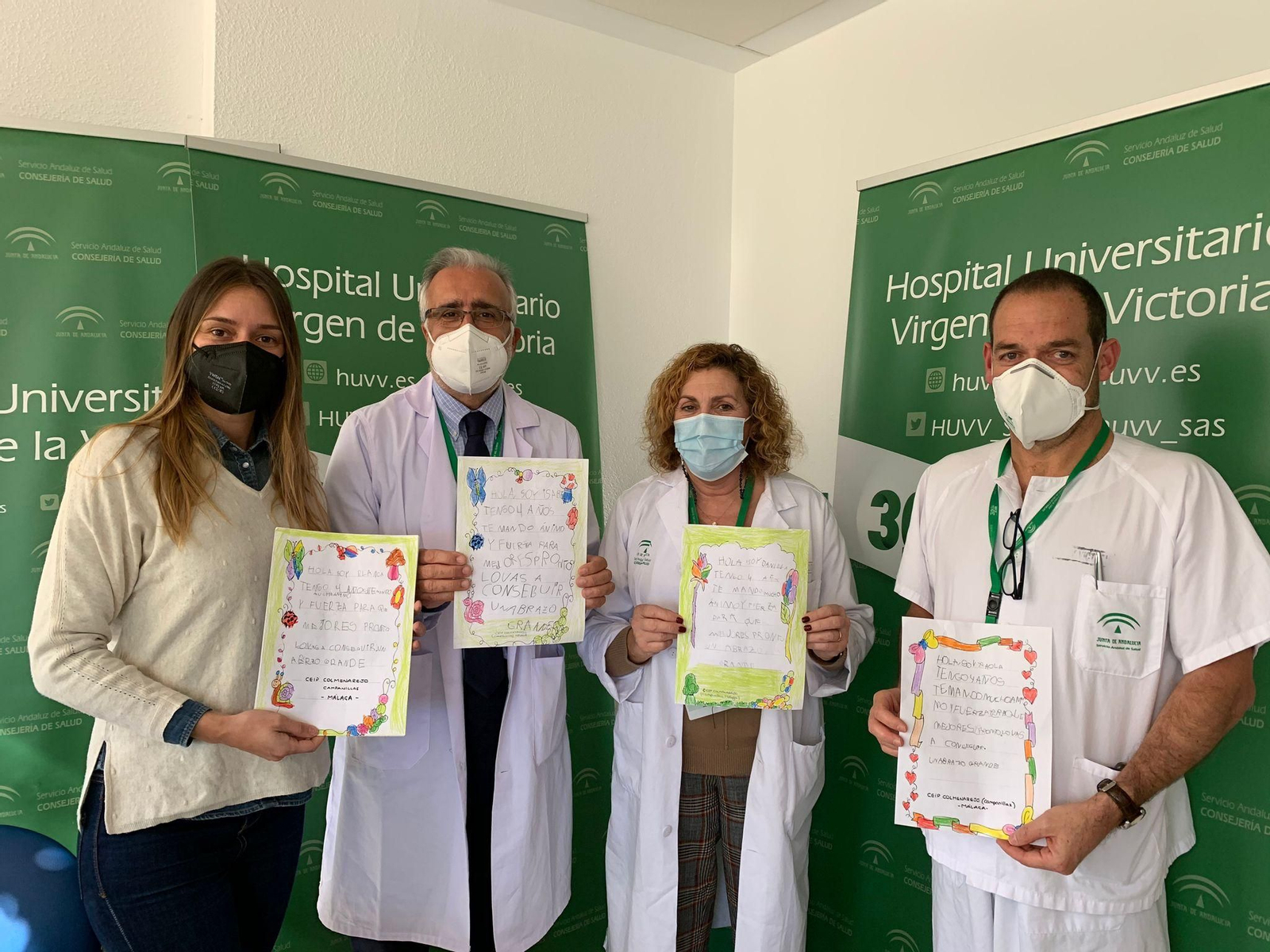 Ana, la maestra del colegio Colmenarejo, y profesionales sanitarios del Clínico muestran los dibujos.