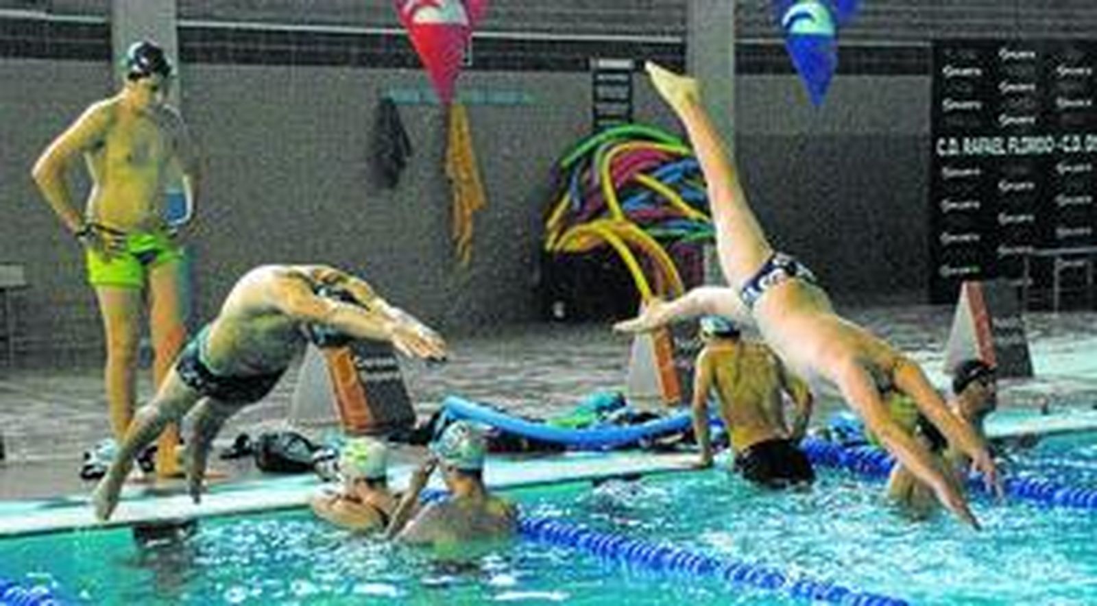 Varios nadadores del Club Natación Portocarrero se lanzan al agua en las instalaciones del Complejo Deportivo Rafael Florido.