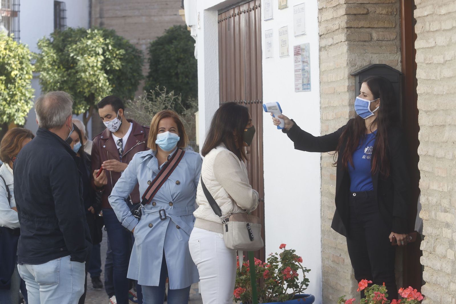 Una controladora toma la temperatura en la entrada a un patio.