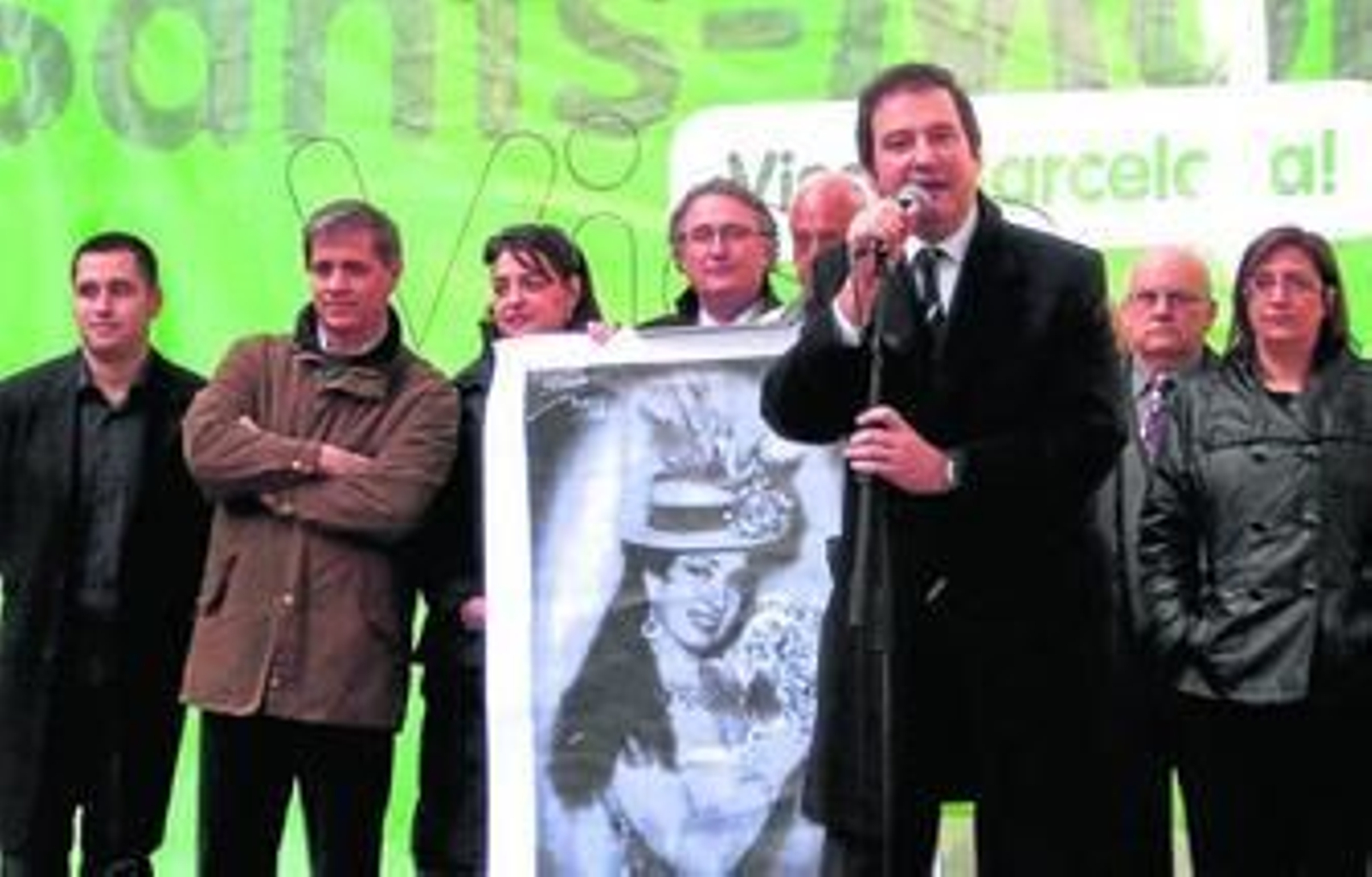 Caicedo portando un cartel con la imagen de la Bella Dorita escucha al alcalde de Barcelona.