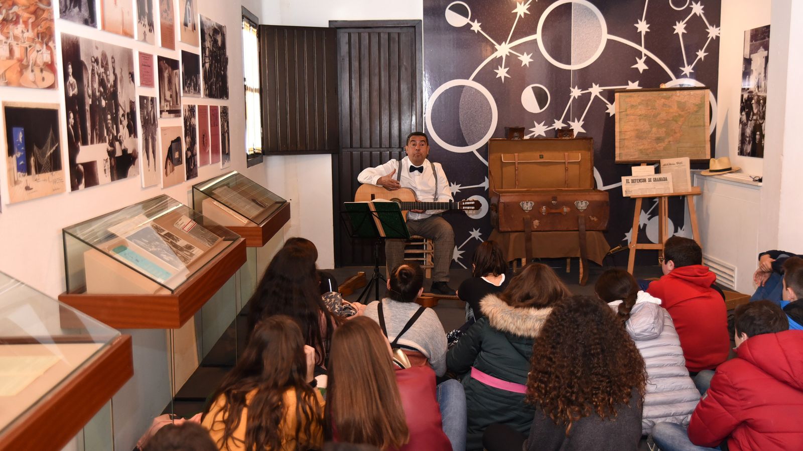 Manuel Mateo con su guitarra y la maleta con la que viaja con los escolares en su taller.
