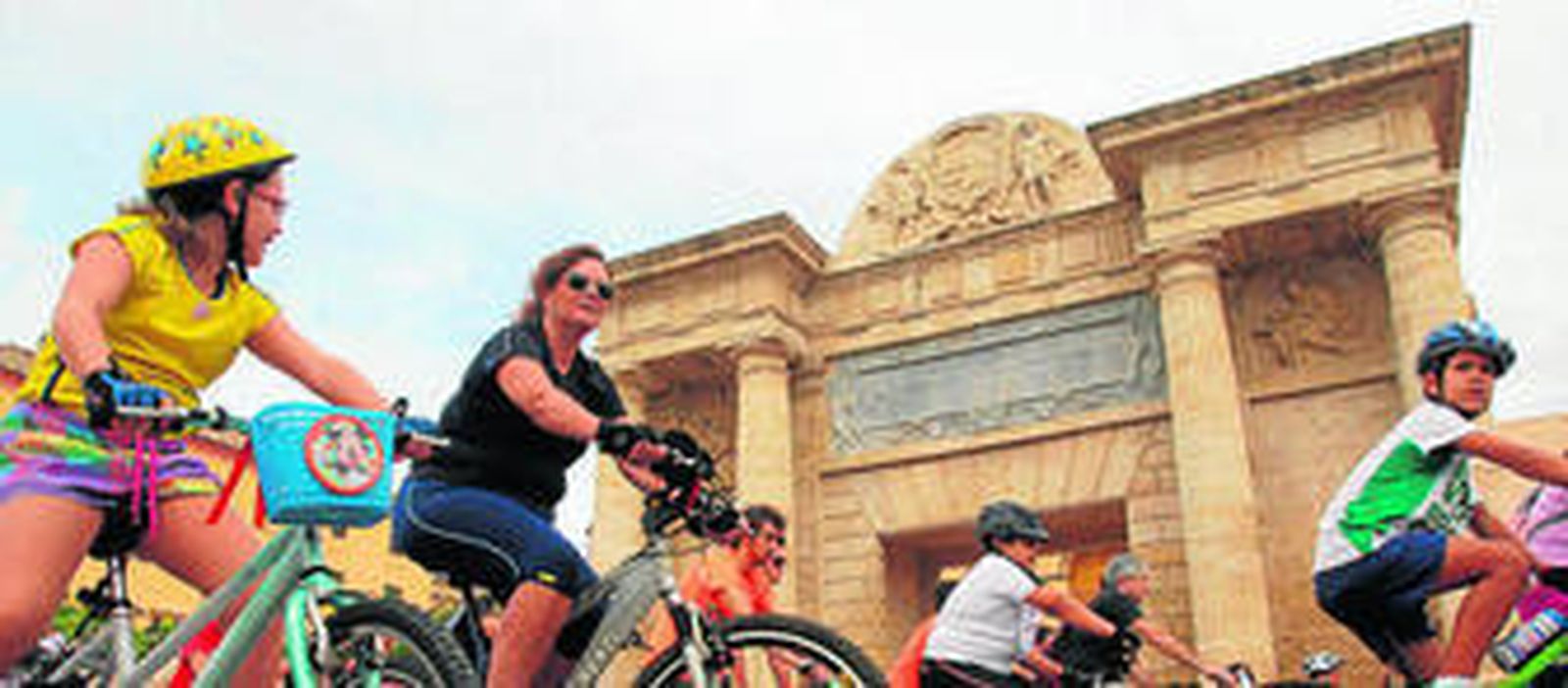 Un grupo de ciclistas pasea por delante de la Puerta del Puente durante el Día de la Bicicleta.