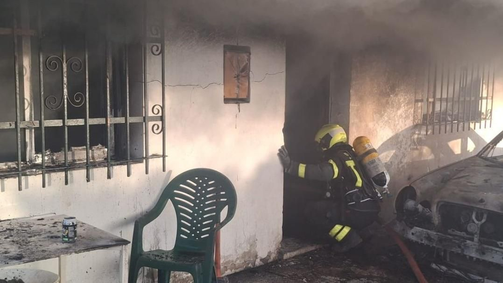 Un bombero interviene en la extinción de un incendio en una vivienda en Chipiona.