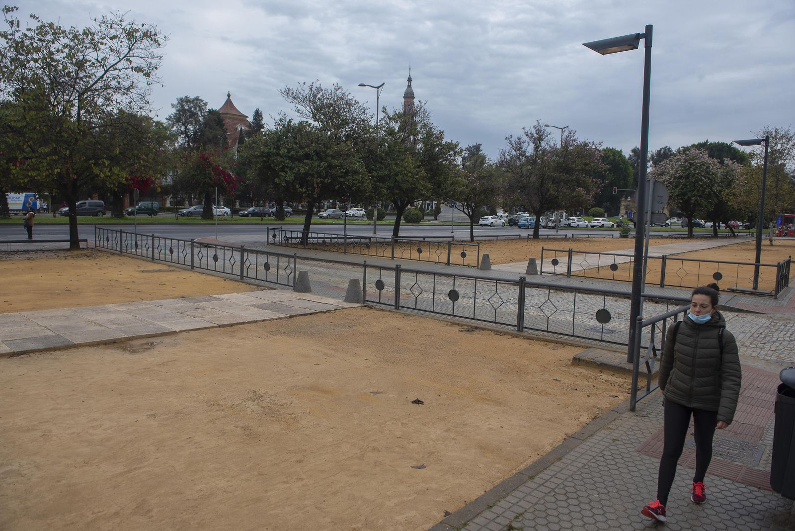 Una mujer camina por el remozado acerado junto al foso de la Universidad de Sevilla.