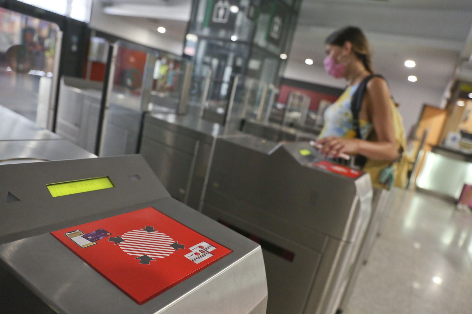 Una joven pasa el torno pagando con el teléfono móvil en el Cercanías de Renfe.