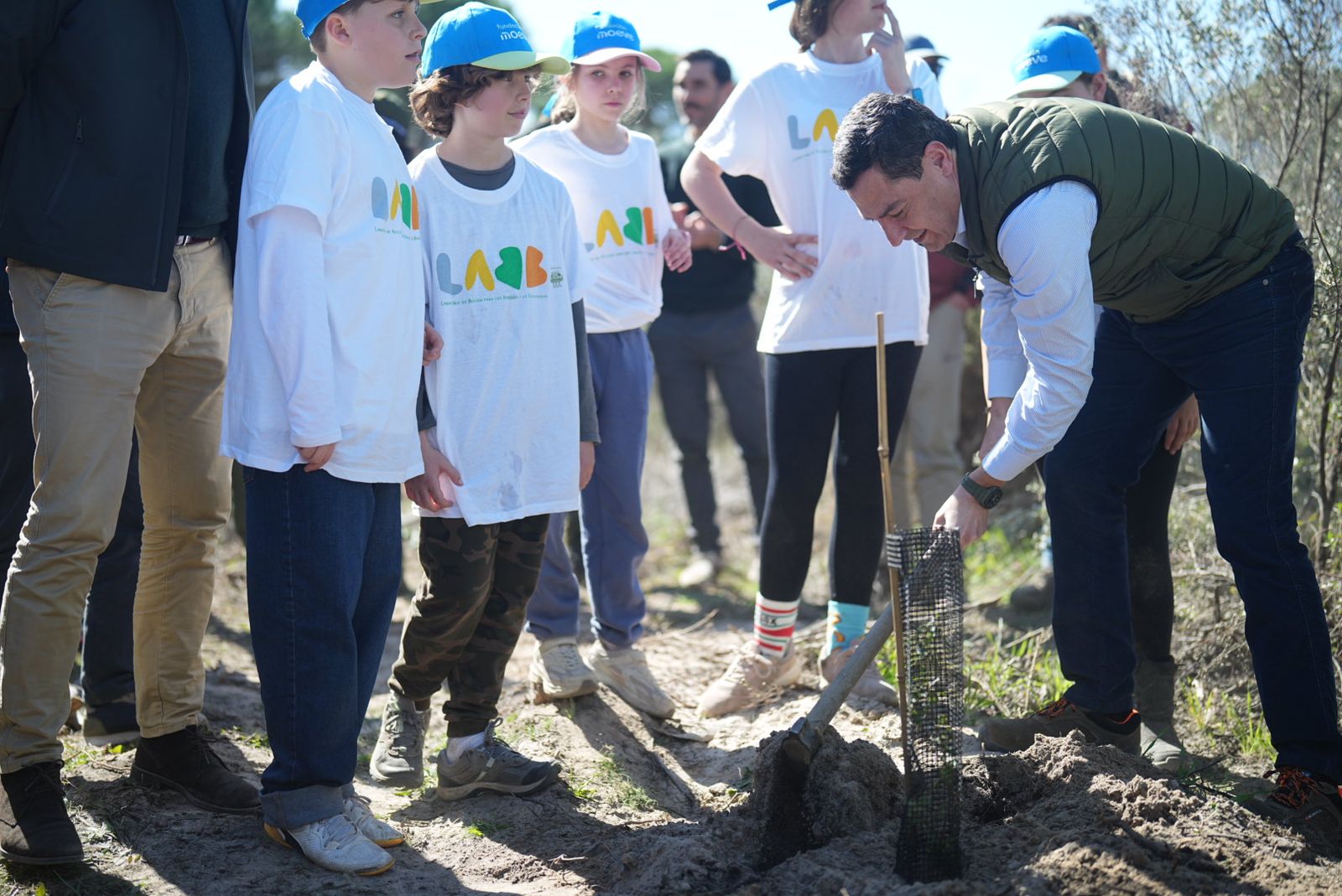 Juanma Moreno junto a los alumnos que participan en una plantación de árboles en el paraje de 'Las Peñuelas'.