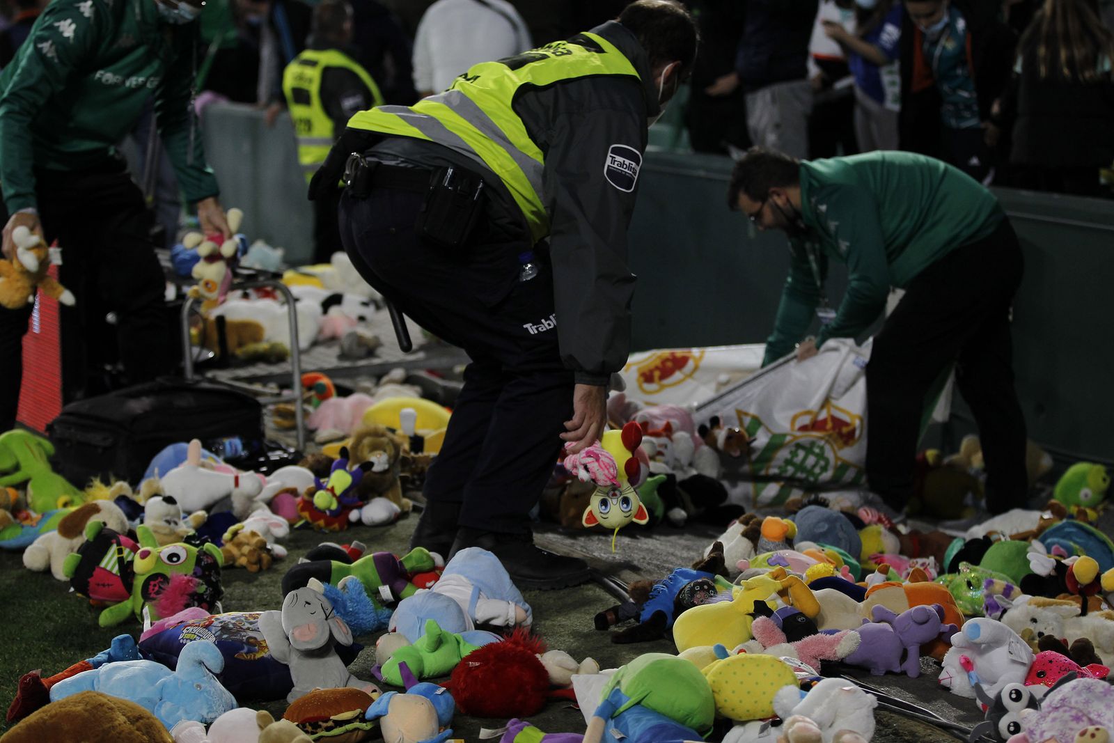 Trabajadores del club recogen los juguetes lanzados en el Betis-Real Sociedad.
