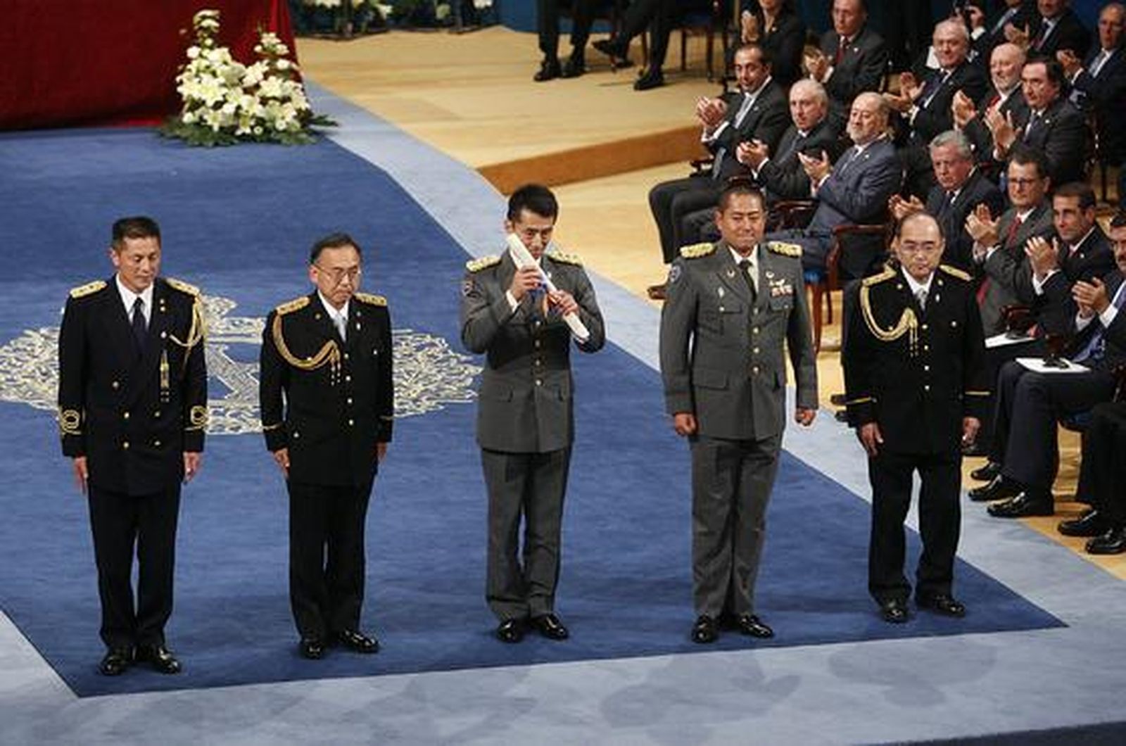 Una representación de los héroes de Fukushima recibe la ovación del público tras recoger el premio de la Concordia. / EFE