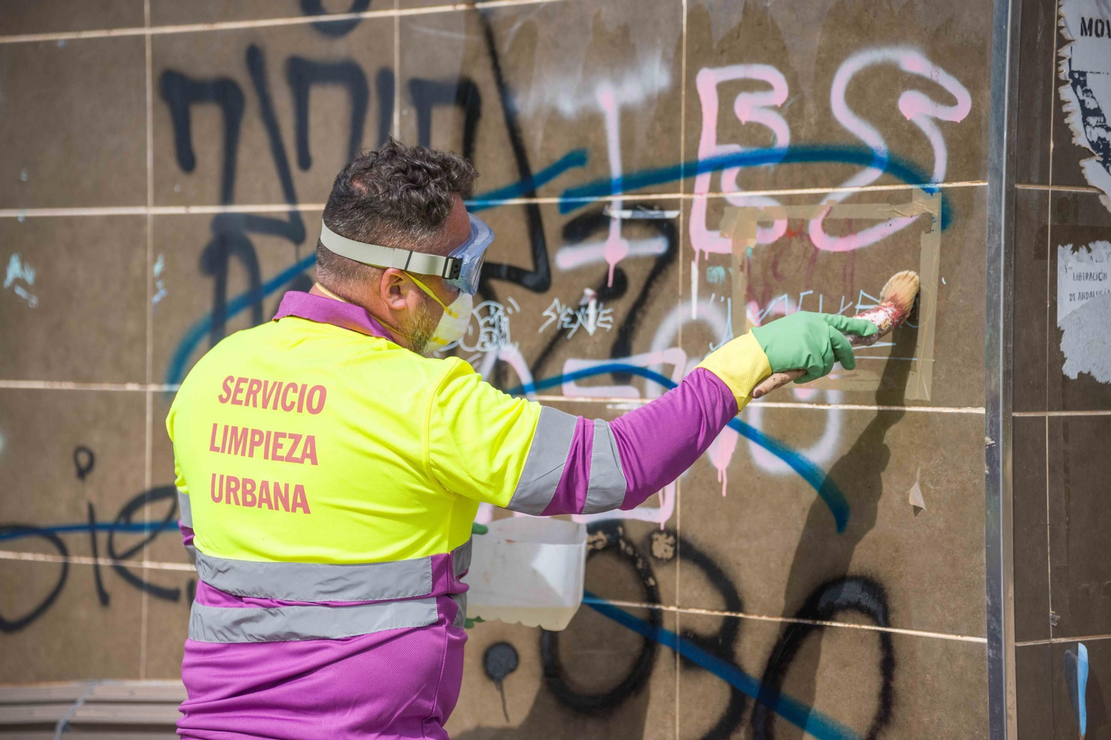 Un trabajador del servicio de limpieza retira un grafiti