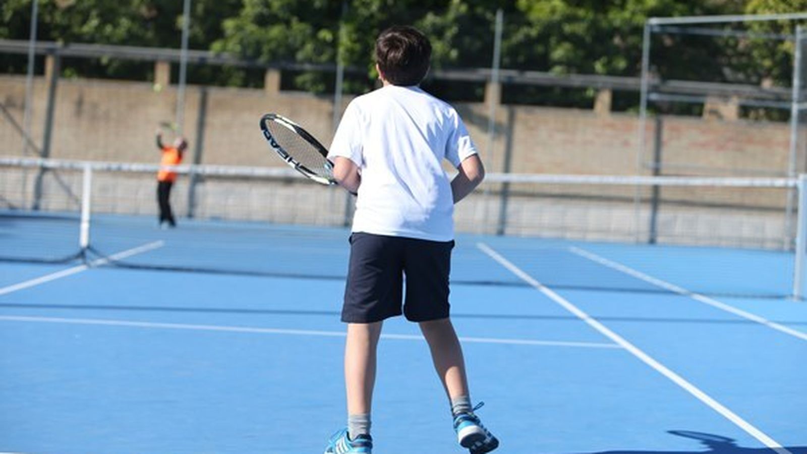 Dos niños juegan al tenis en una pista del IMD.