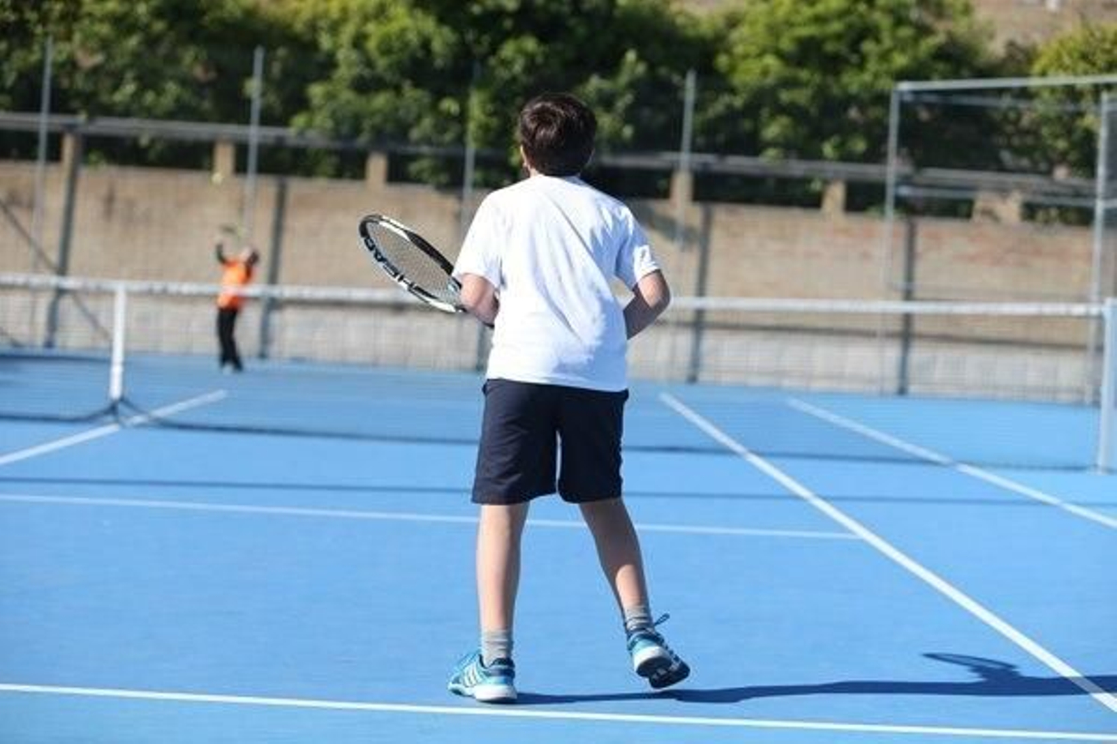 Dos niños juegan al tenis en una pista del IMD.