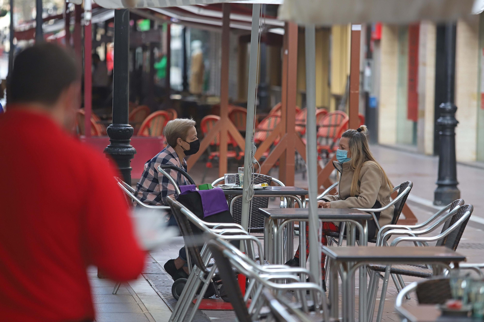 Dos mujeres con mascarilla charlan en una terraza de La Línea.