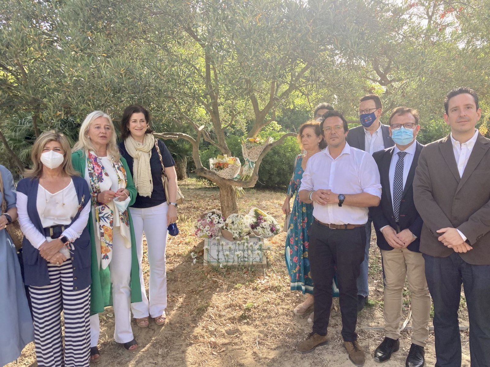 Autoridades y representantes de asociaciones posan ante el Árbol de la Solidaridad tras la ofrenda.
