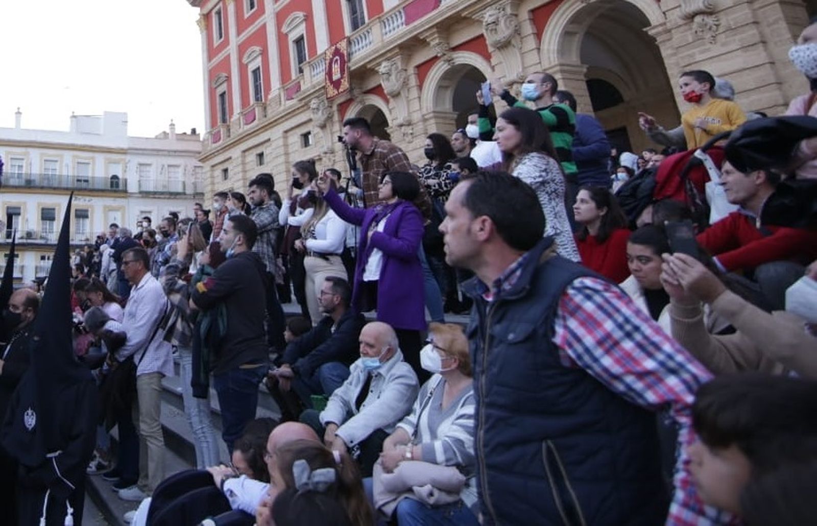 Ciudadanos en las escaleras del Ayuntamiento de San Fernando al paso de una hermandad.