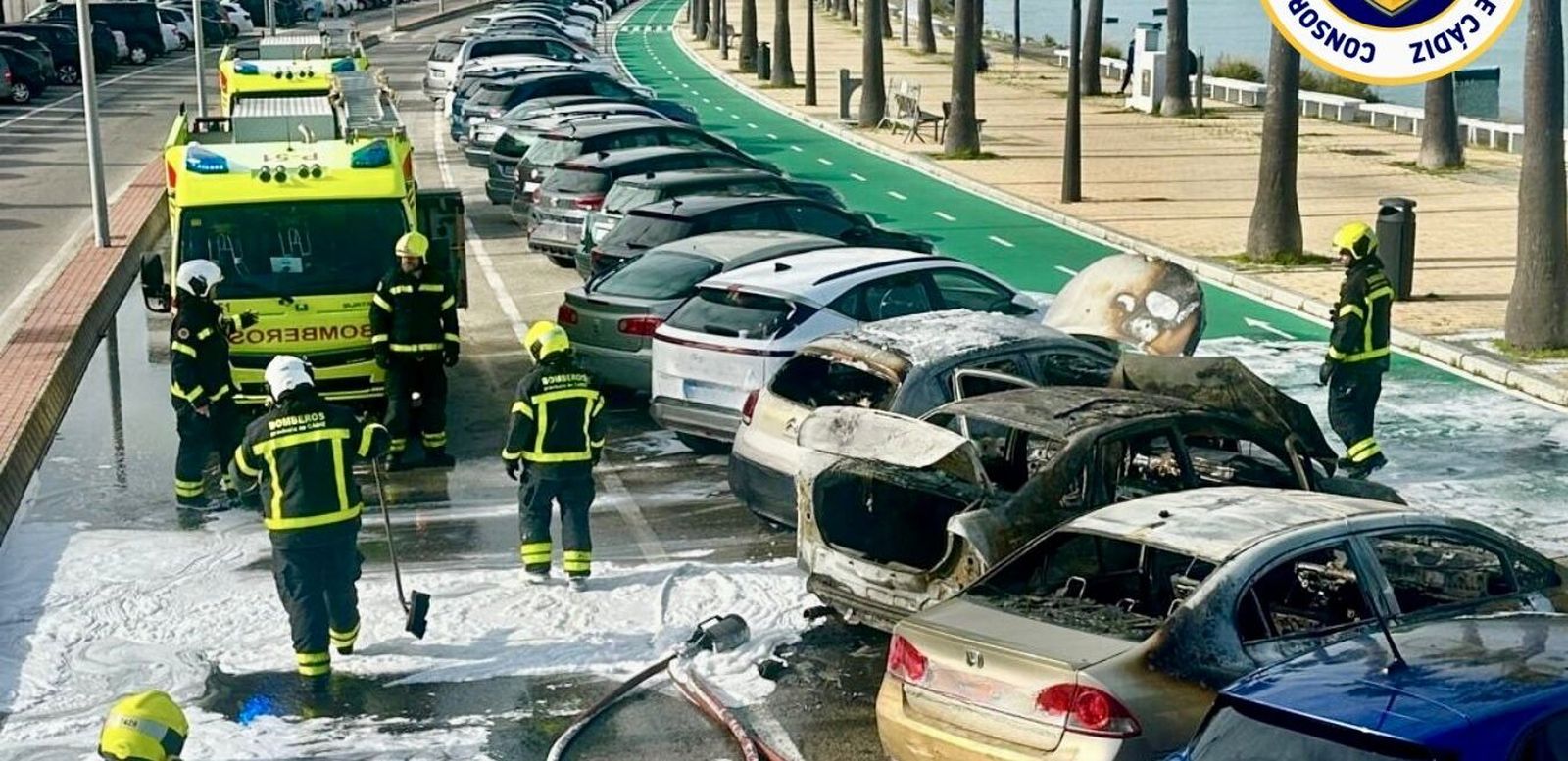 Los bomberos junto a los coches afect6ados en la avenida de la Bahía.