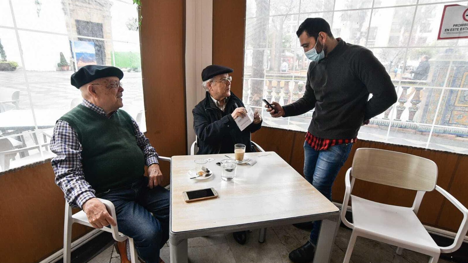 Un camarero lee con su móvil el certificado covid de un cliente hace unas semanas.