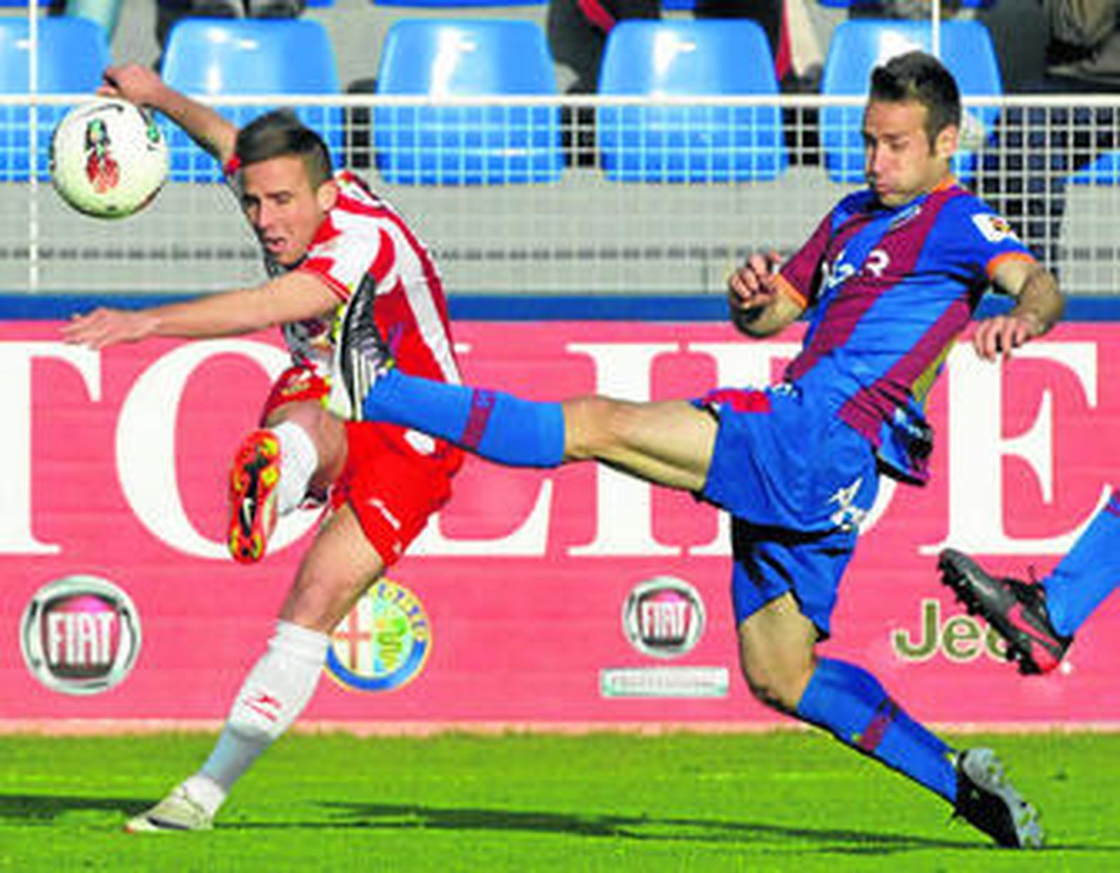 El almeriense Aarón le pega al balón encimado por un defensor del Huesca.