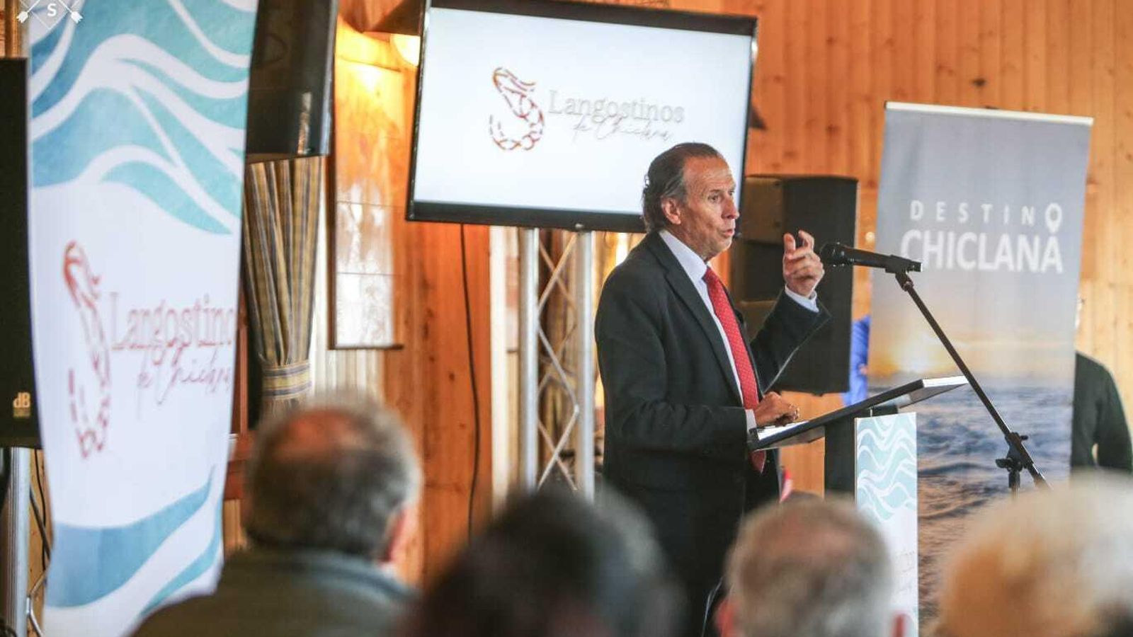 El alcalde de Chiclana, José María Román, durante su intervención con el logotipo de la marca detrás.