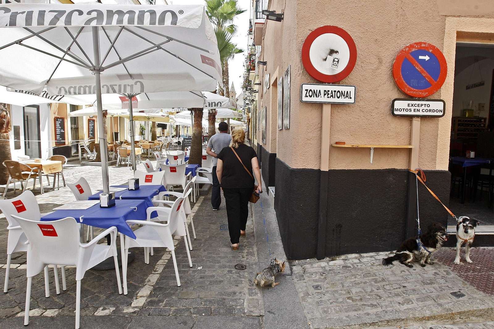 Unos vecinos atraviesan la zona peatonal de la que advierte la señal de tráfico en la calle de La Palma, repleta de terrazas de bares.