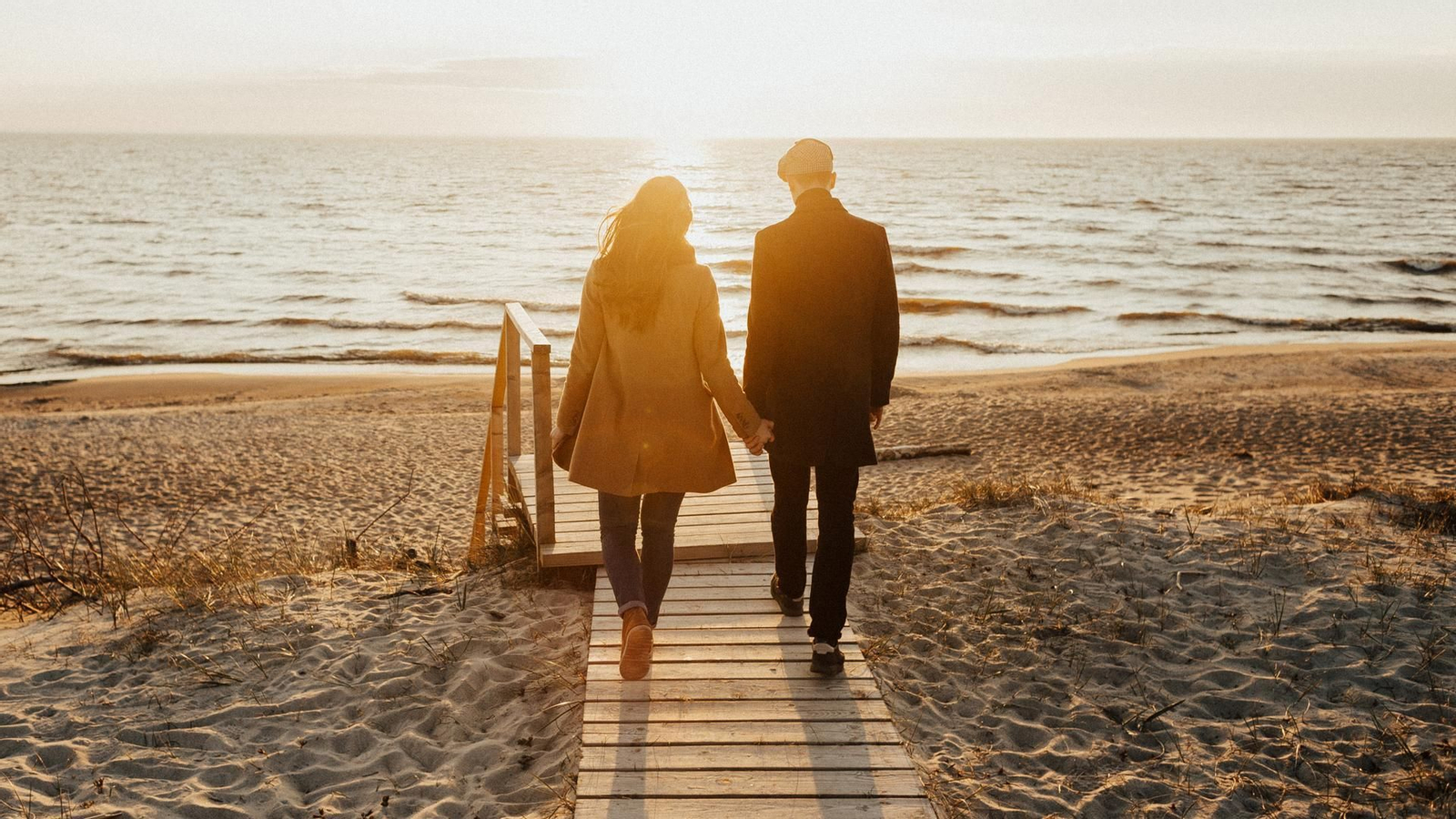 Pareja paseando de la mano en la playa.