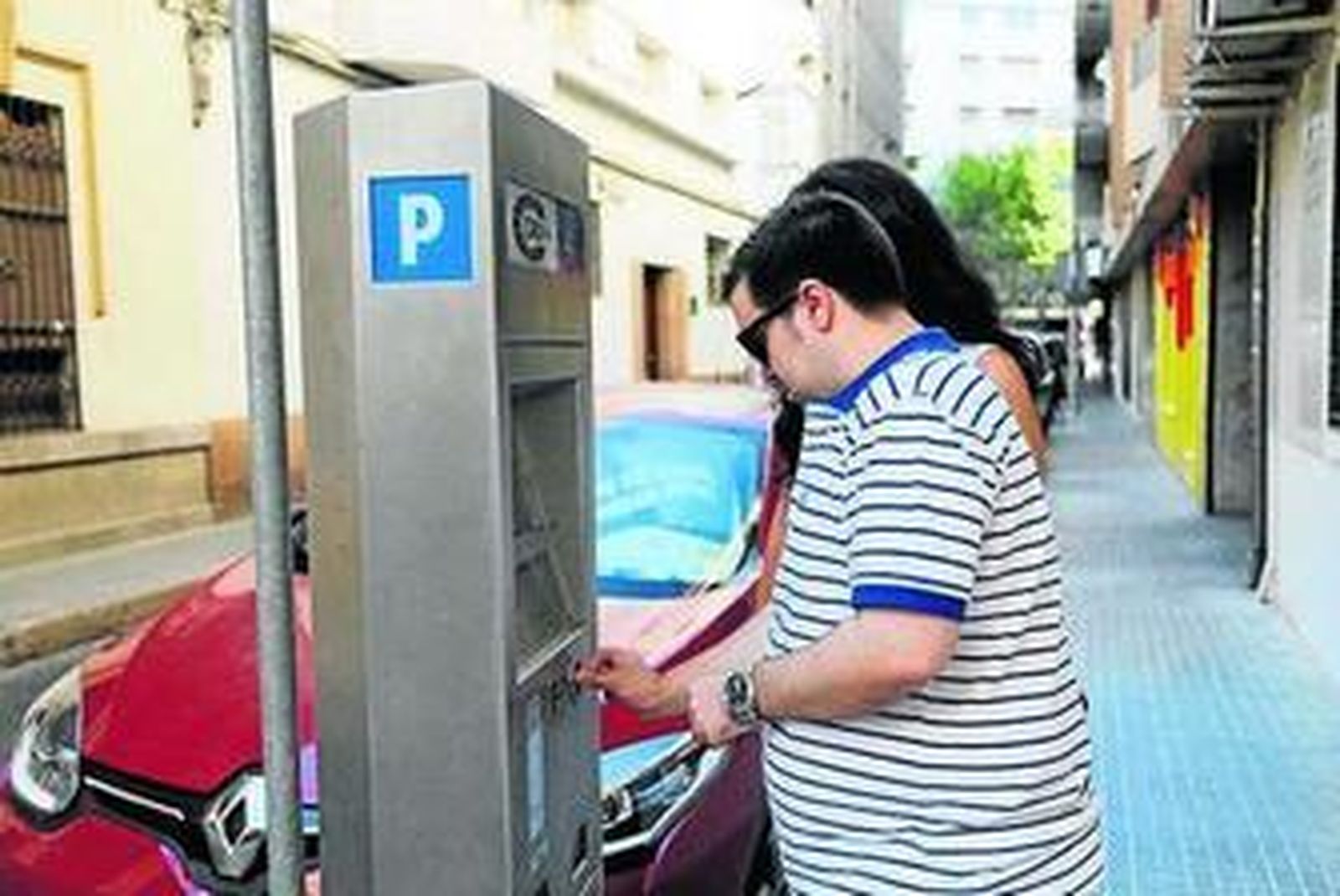 Una pareja paga la zona azul en una calle de la capital.
