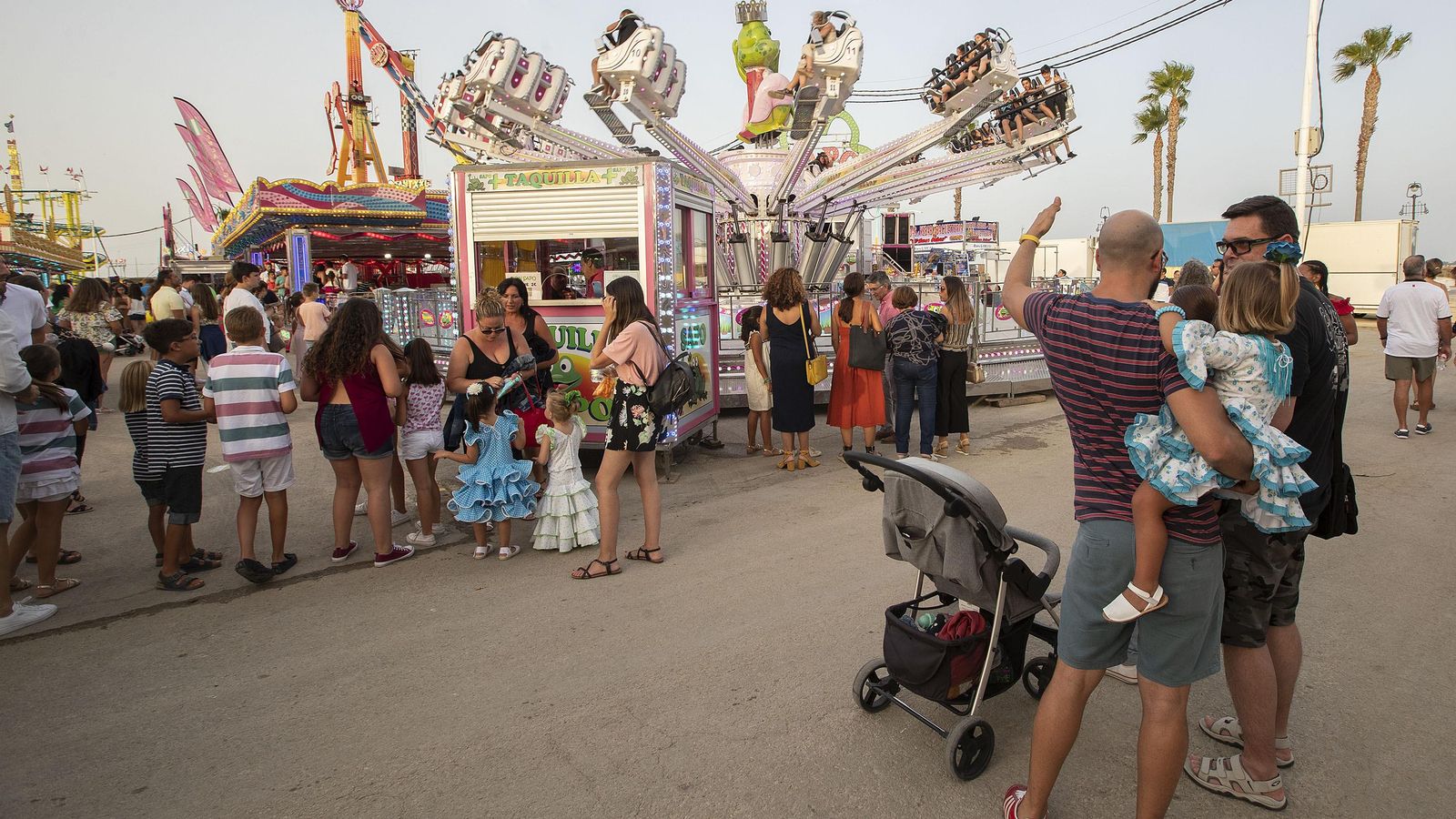 Algunos niños hacen cola con sus madres para subirse a una atracción.