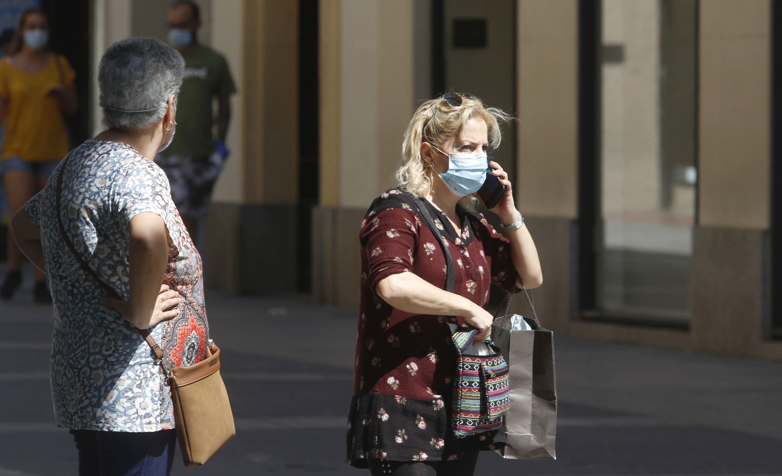 Una mujer habla por teléfono con una mascarilla puesta.
