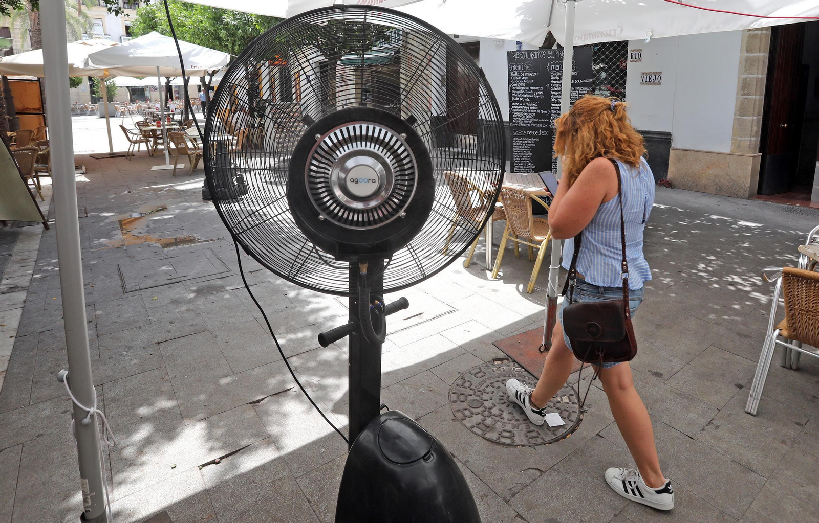 Una joven pasa ayer ante un ventilador con vaporizador de agua instalado en una terraza del Arenal.