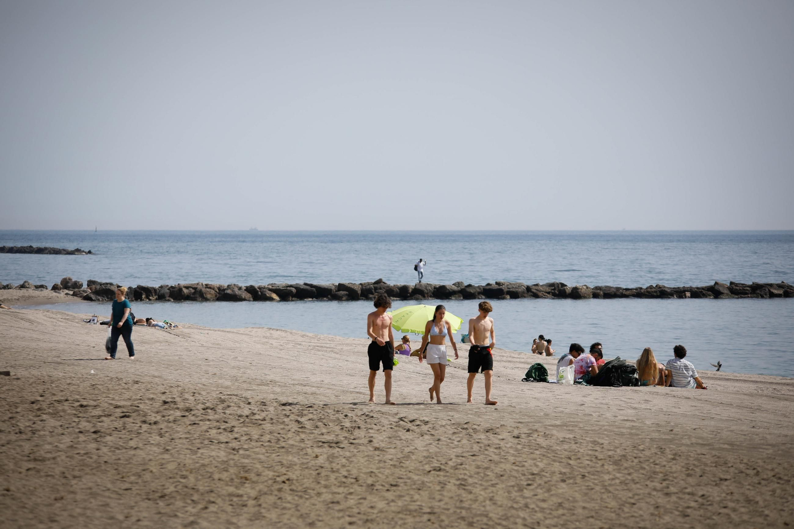 Un grupo de chavales camina sobre la arena de la playa  de San Miguel durante un día veraniego.