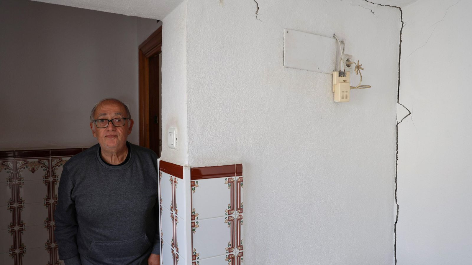 Un vecino posa en el rellano, junto a una gran fisura.