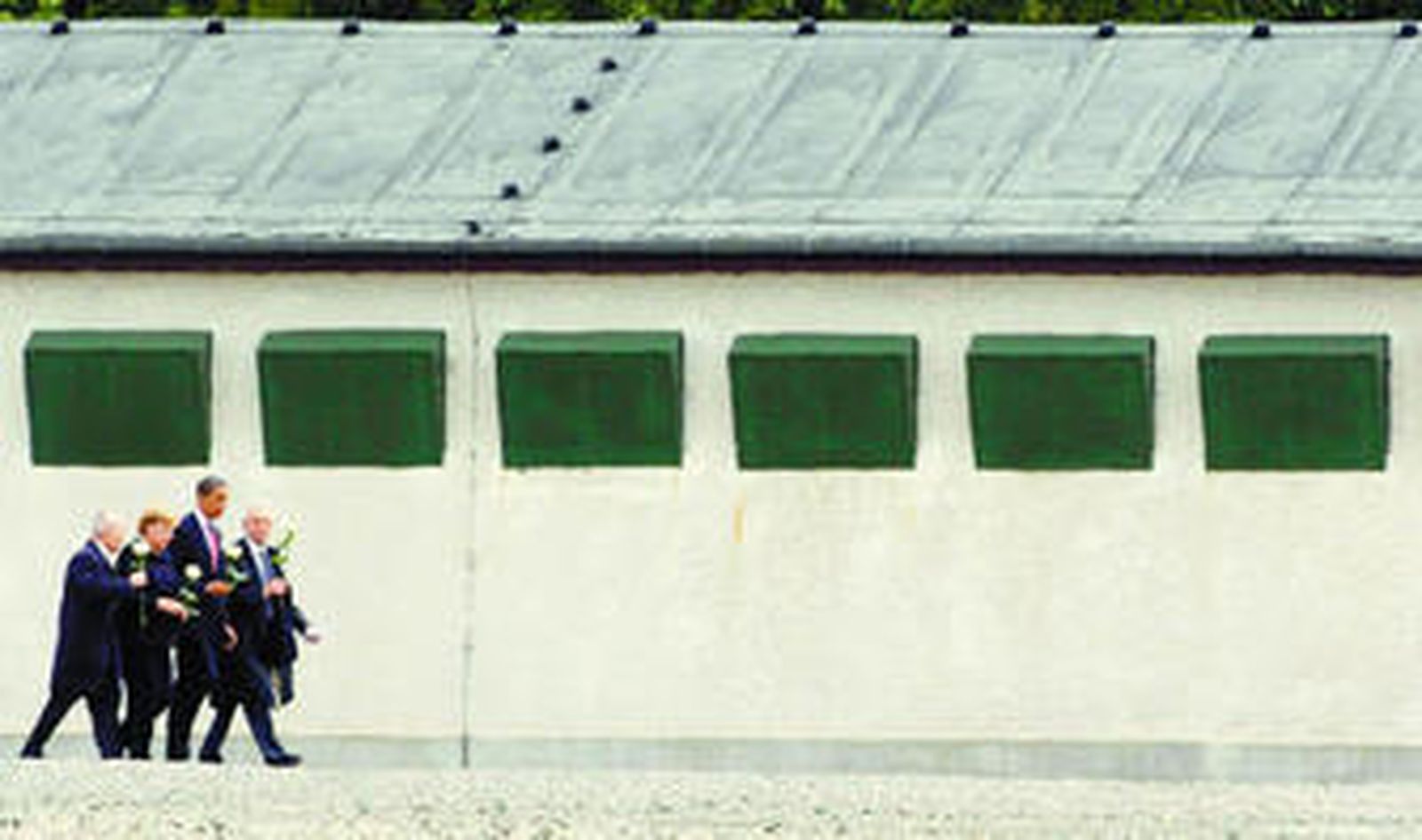 Obama, Merkel y dos de los supervivientes pasan ante uno de los barracones del campo de exterminio nazi de Buchenwald.