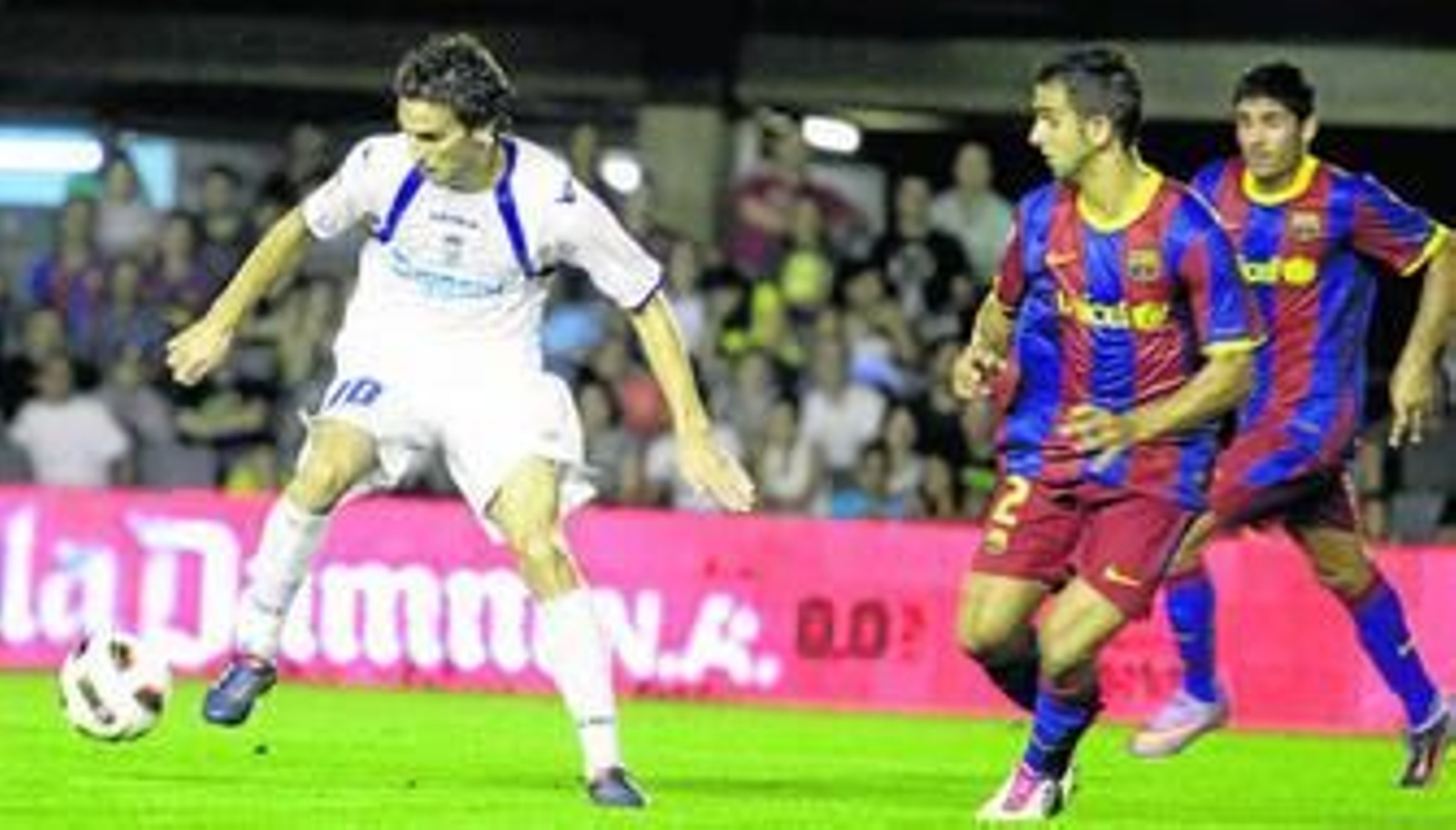 Óscar Díaz controla el balón seguido de cerca por el barcelonista Montoya.