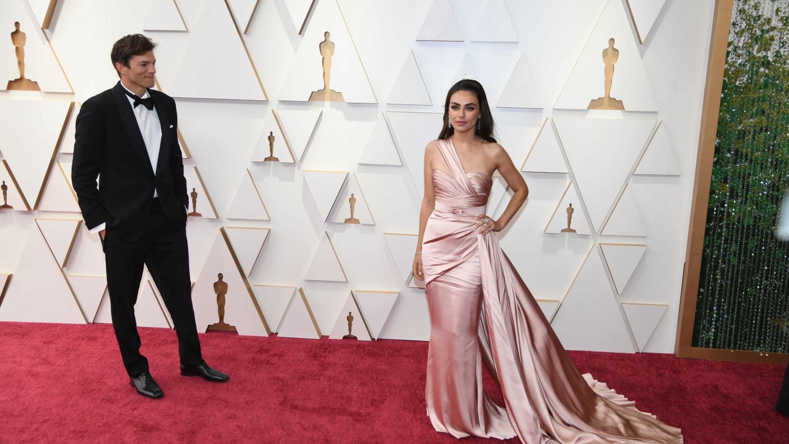 Mila Kunis posa en la alfombra bajo la atenta mirada de su esposo, Ashton Kutcher.