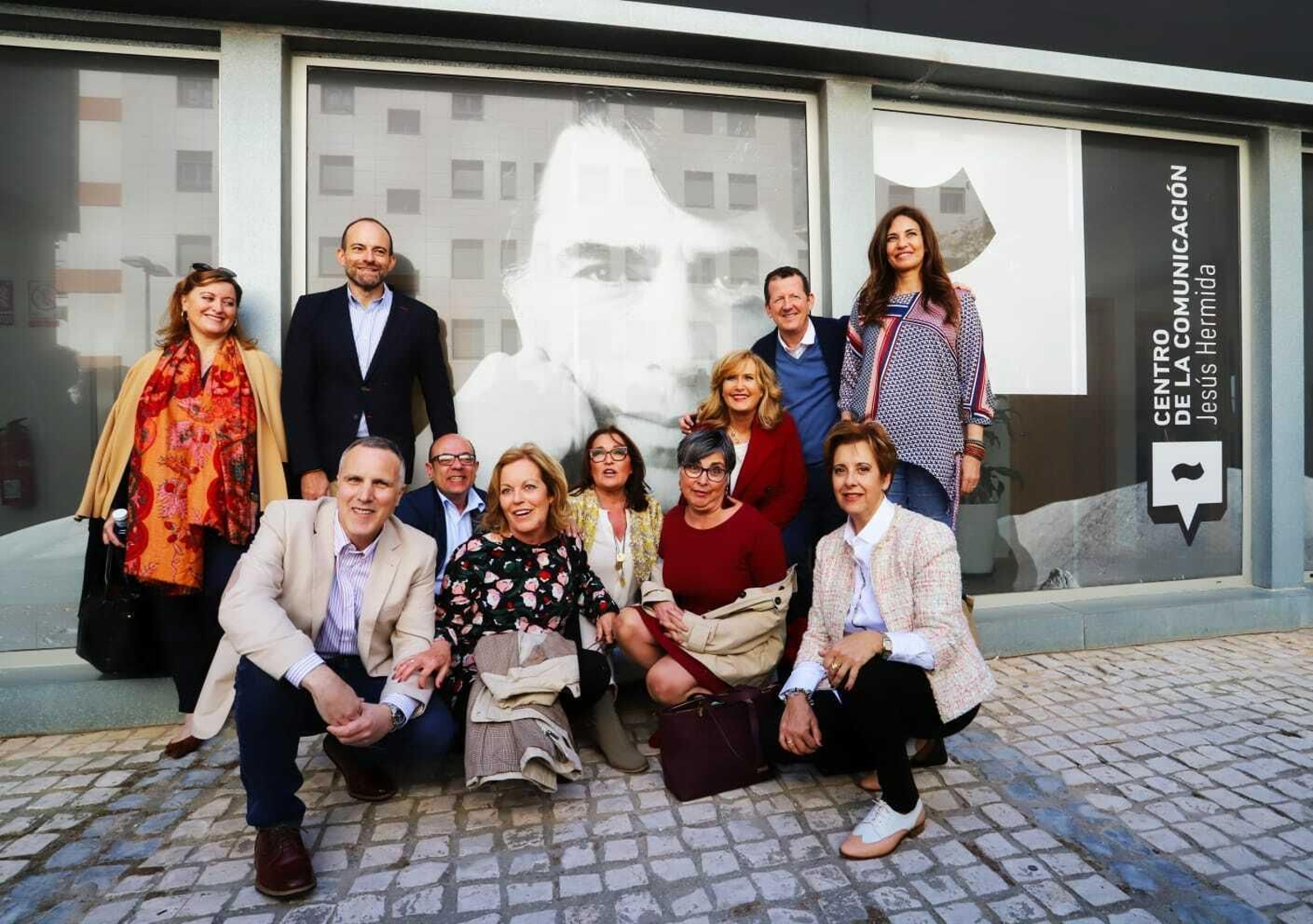 Familiares y amigos de Jesús Hermida posan junto a su retrato en la fachada del centro.