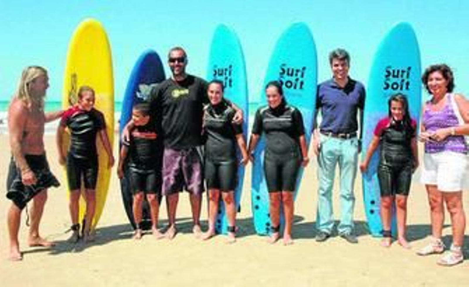 Romero y Ortega posan junto a los jóvenes surferos en la playa de Camposoto.