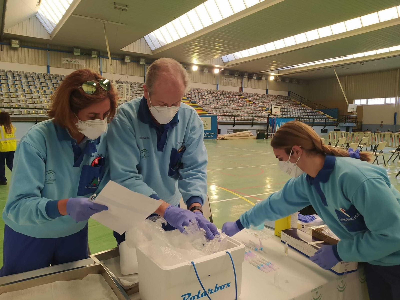 Tres sanitarios preparando varias dosis de vacunas en un centro deportivo de Almería