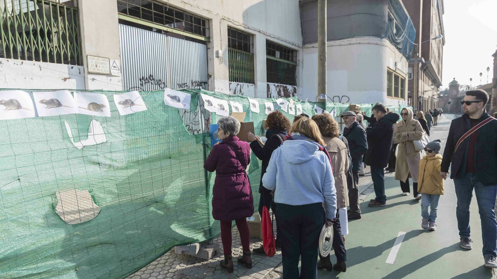 Un momento de la protesta, en la que se han colocado dibujos de ratas y otros elementos de denuncia en la valla que rodea al edificio..