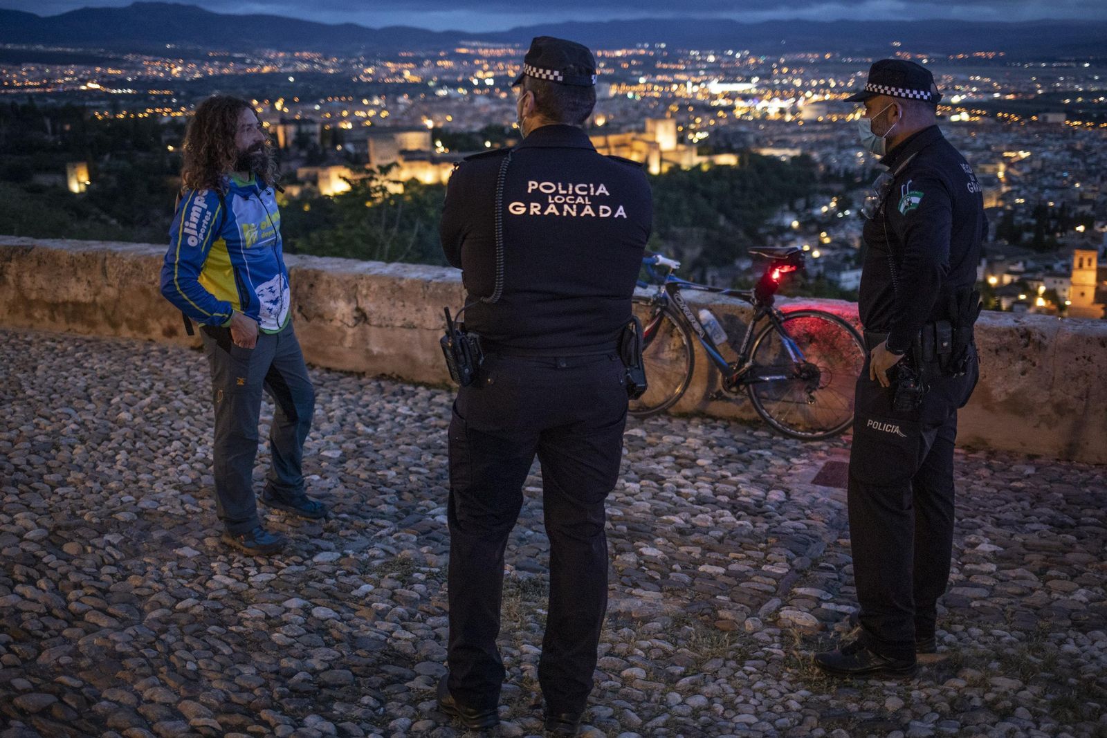 Dos agentes de la Policía Local de Granada conversan con un ciclista en la ciudad.